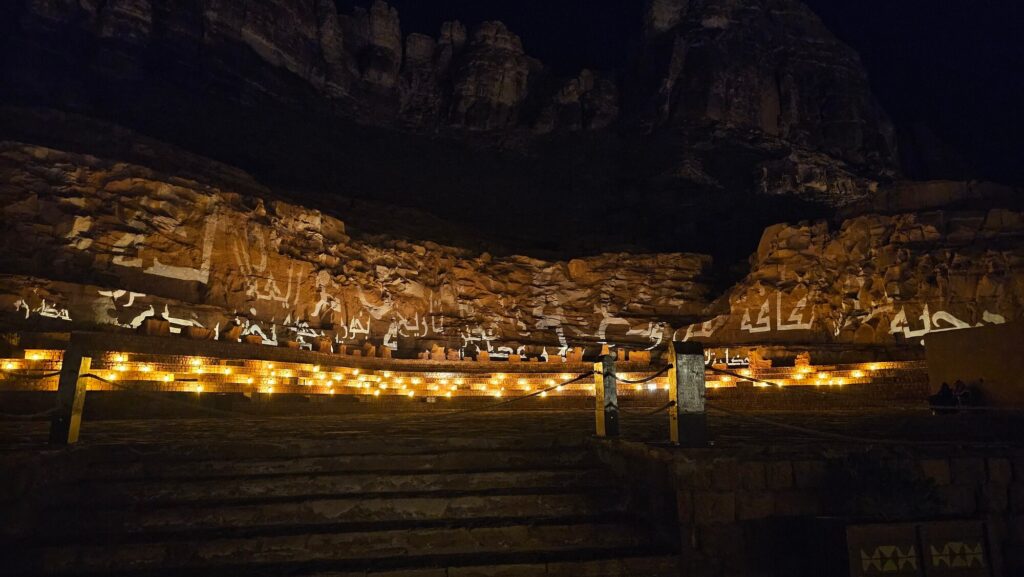 Desert rock formations illuminated with Arabic projections and candlelight at an outdoor night event
